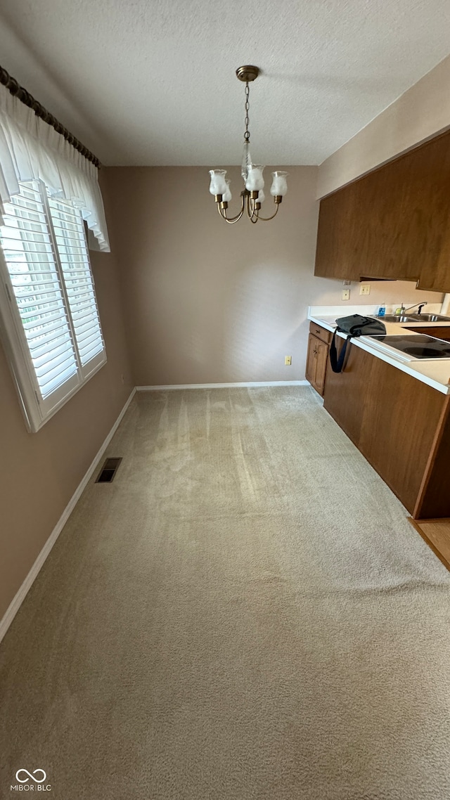 unfurnished dining area featuring carpet floors, a textured ceiling, and a notable chandelier