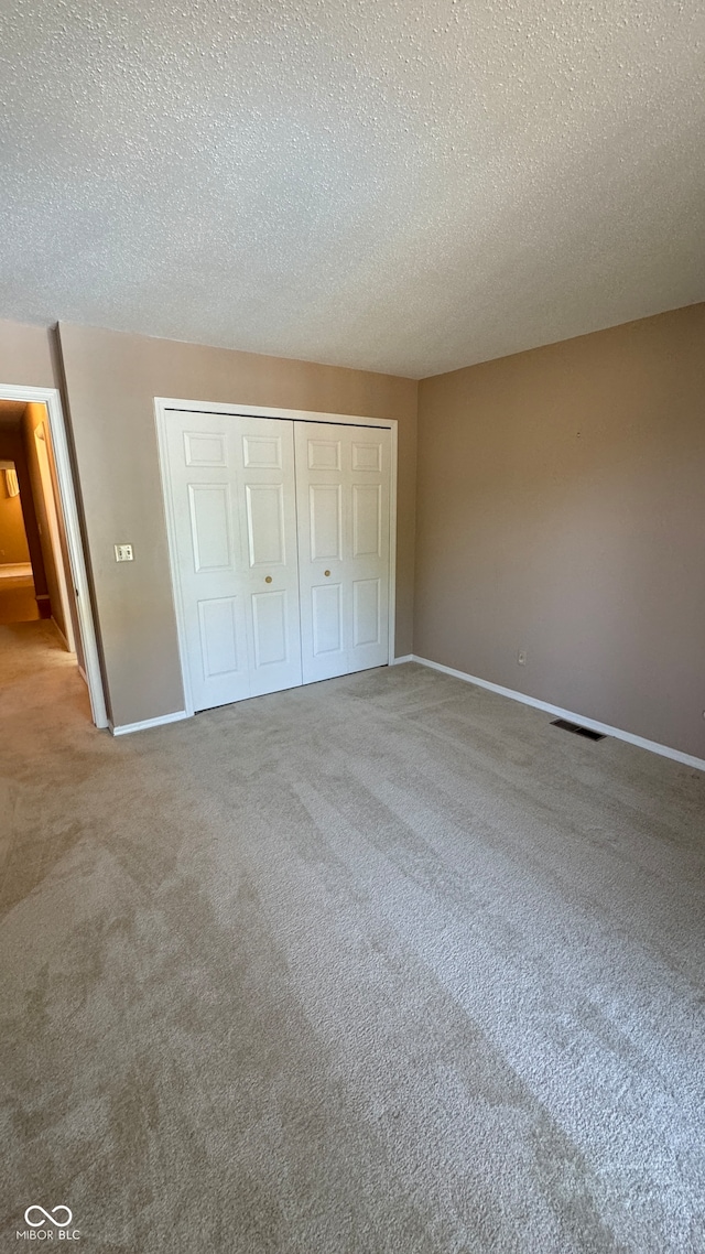 unfurnished bedroom featuring a closet, carpet floors, and a textured ceiling