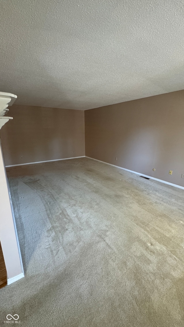 carpeted empty room with a textured ceiling