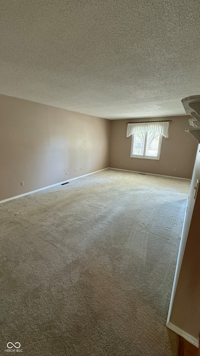 carpeted empty room featuring a textured ceiling