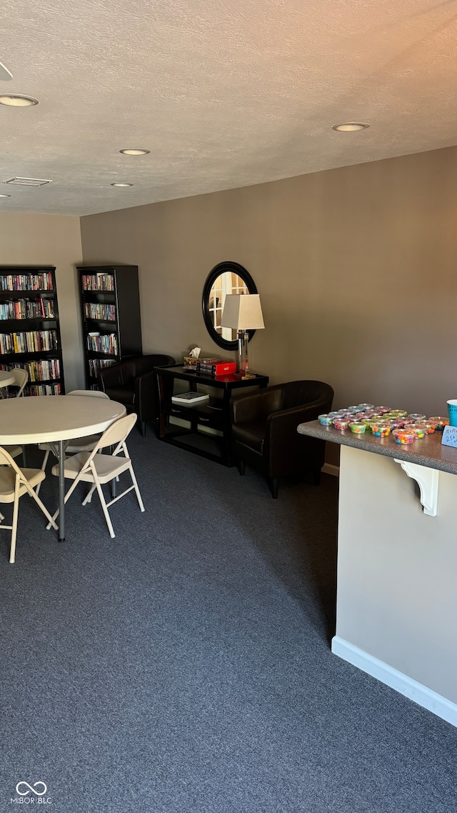 interior space featuring a textured ceiling and dark colored carpet