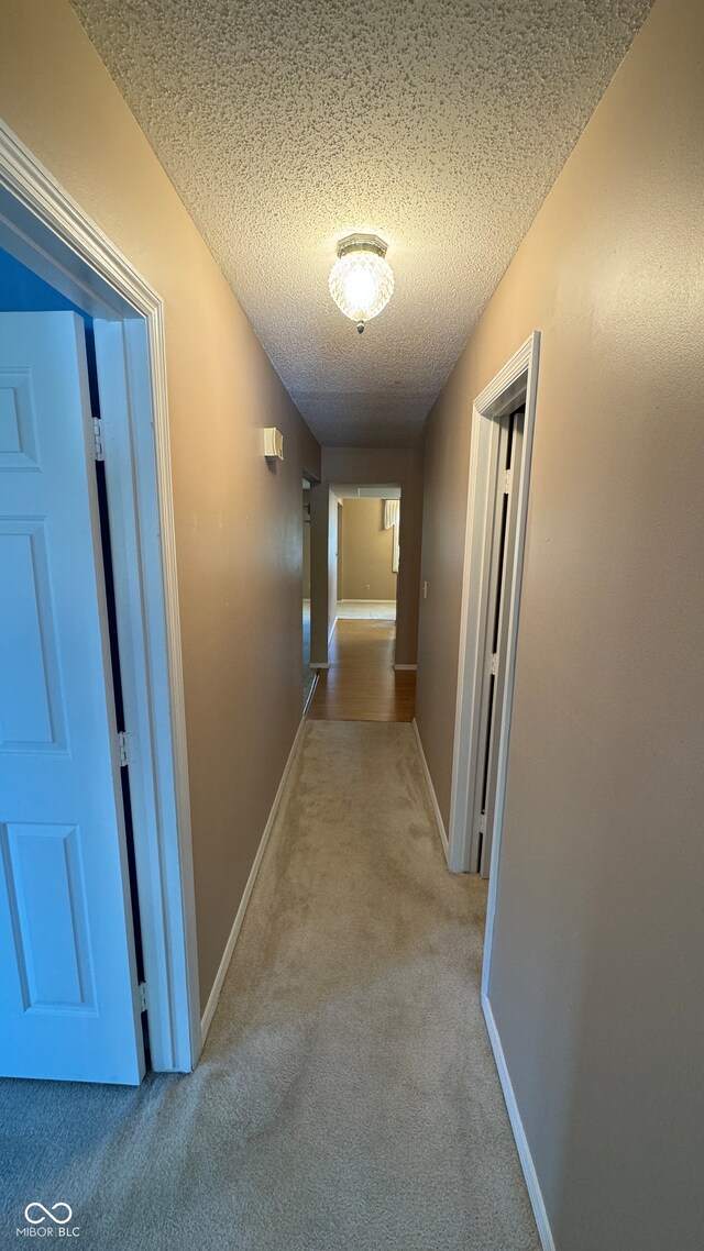 hall featuring a textured ceiling and light carpet