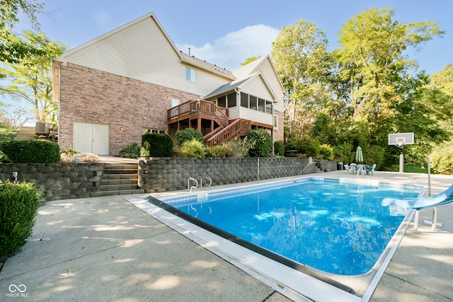 view of swimming pool featuring a wooden deck, a patio, and a water slide