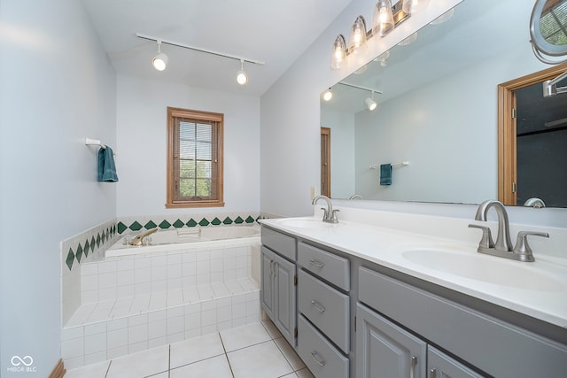 bathroom featuring tiled tub, vanity, tile patterned flooring, and track lighting