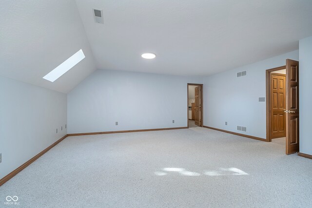 additional living space featuring vaulted ceiling with skylight and light carpet