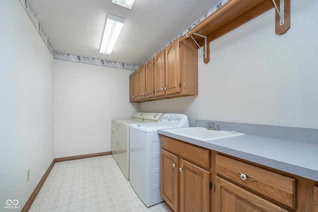 laundry area featuring a textured ceiling, sink, independent washer and dryer, and cabinets