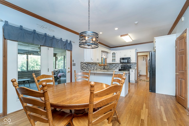 dining area featuring an inviting chandelier, light wood-type flooring, sink, and crown molding