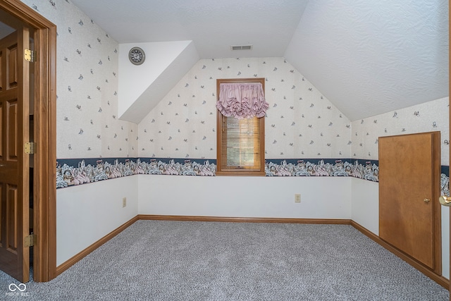 bonus room with vaulted ceiling, a textured ceiling, and carpet floors