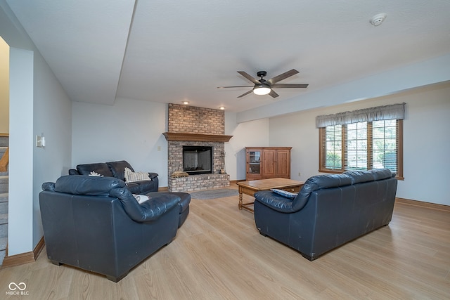 living room featuring light hardwood / wood-style floors, ceiling fan, and a fireplace