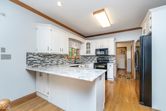 kitchen with black appliances, kitchen peninsula, and white cabinetry