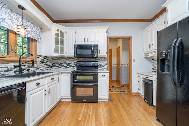 kitchen featuring light hardwood / wood-style floors, white cabinetry, black appliances, decorative light fixtures, and sink