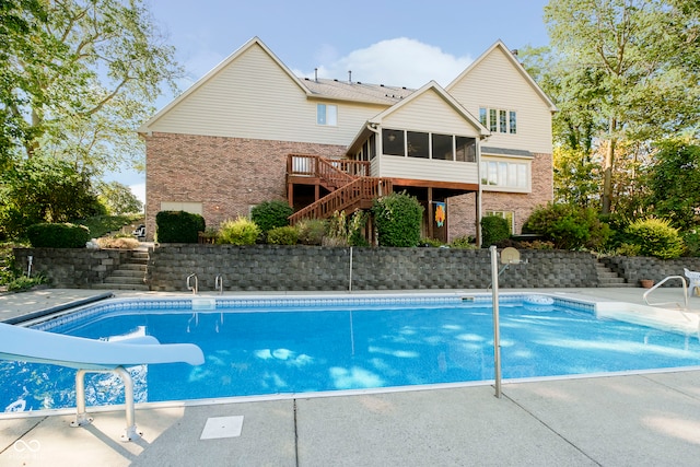 view of swimming pool featuring a sunroom, a patio, a water slide, and a deck