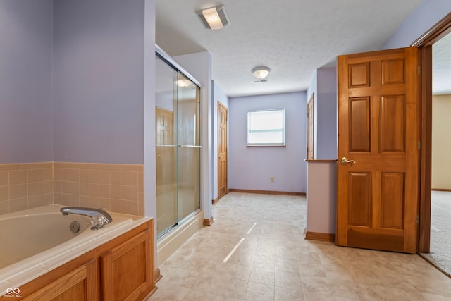 bathroom with shower with separate bathtub and a textured ceiling