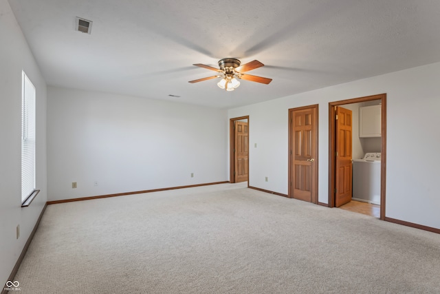 unfurnished bedroom with connected bathroom, ceiling fan, light colored carpet, and washer / dryer