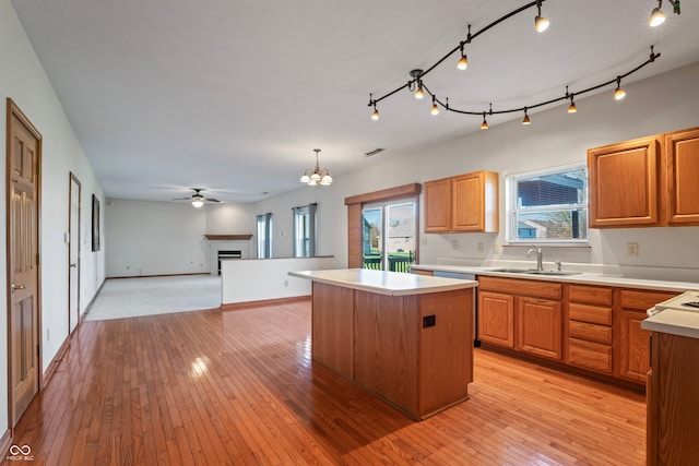 kitchen with a center island, sink, light hardwood / wood-style floors, decorative light fixtures, and ceiling fan with notable chandelier