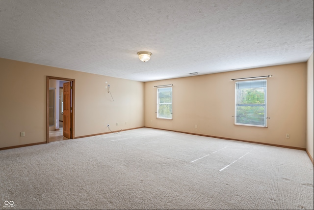 empty room with light colored carpet and a textured ceiling