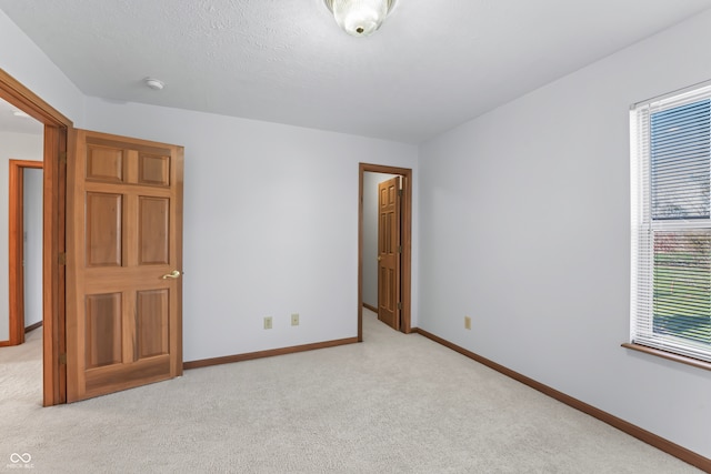 unfurnished bedroom with light carpet and a textured ceiling