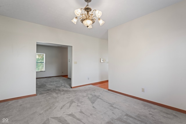 carpeted empty room featuring a chandelier