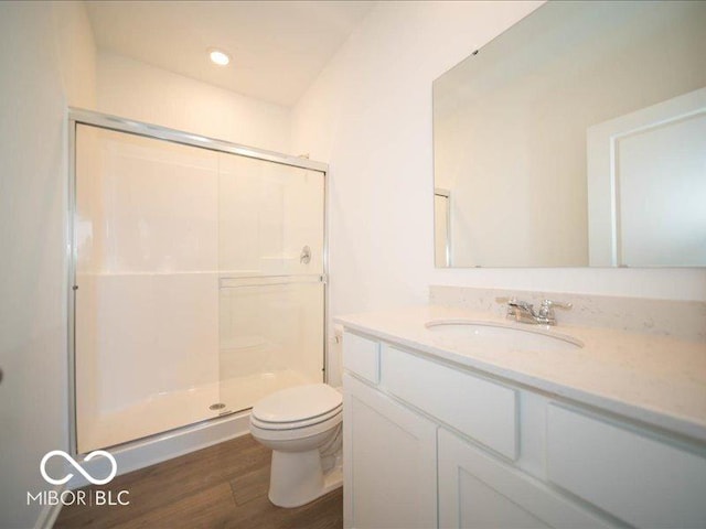 bathroom with toilet, a shower stall, wood finished floors, and vanity