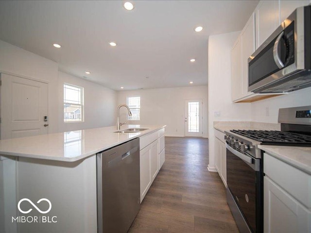 kitchen featuring white cabinets, an island with sink, dark wood-style floors, appliances with stainless steel finishes, and a sink