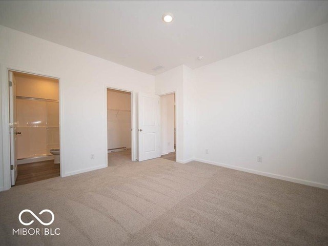 unfurnished bedroom featuring a spacious closet, carpet, connected bathroom, and baseboards