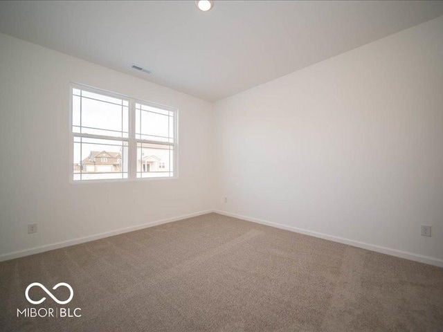 carpeted spare room with visible vents and baseboards