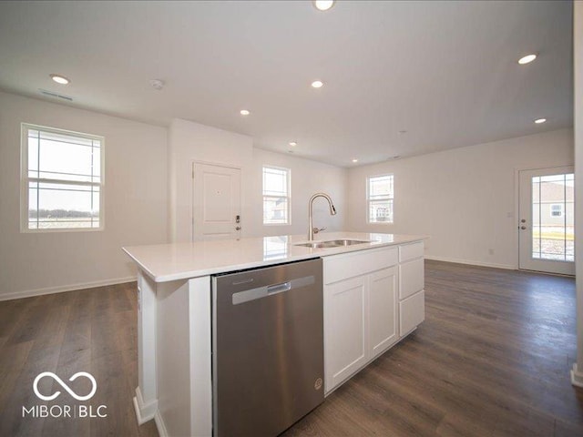 kitchen featuring a kitchen island with sink, dark wood-type flooring, a sink, light countertops, and stainless steel dishwasher