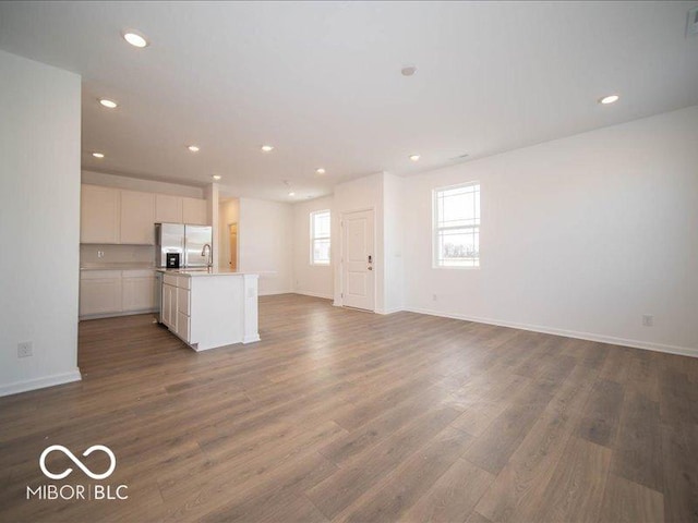 unfurnished living room with recessed lighting, visible vents, dark wood finished floors, and baseboards