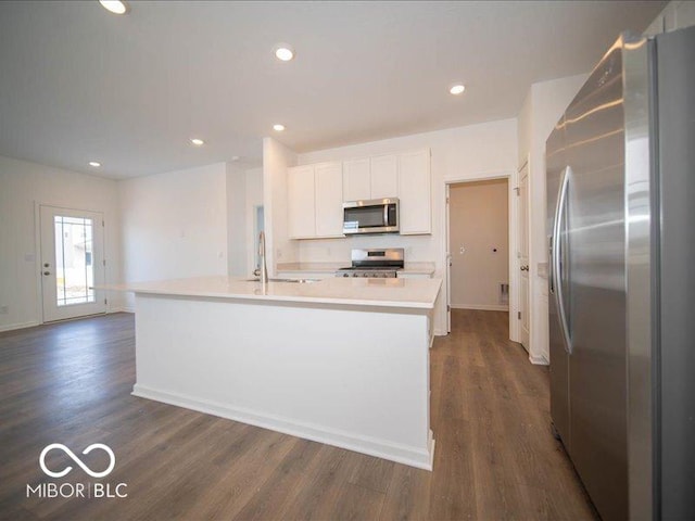 kitchen with white cabinets, appliances with stainless steel finishes, dark wood-type flooring, light countertops, and a sink