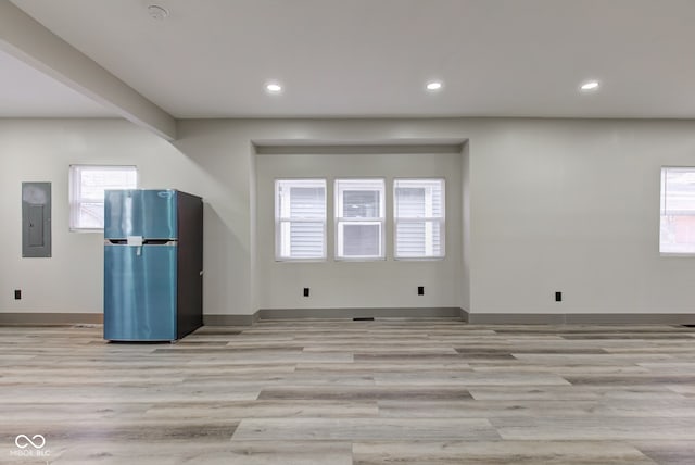 empty room with electric panel, light hardwood / wood-style floors, and plenty of natural light