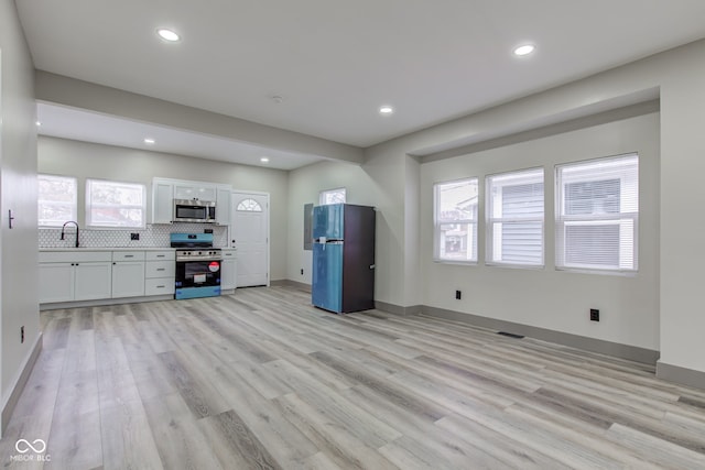 interior space with white cabinetry, a healthy amount of sunlight, appliances with stainless steel finishes, and light hardwood / wood-style flooring