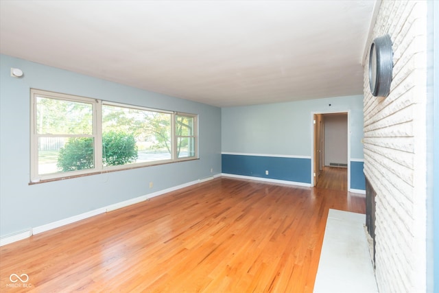 unfurnished room with a brick fireplace and hardwood / wood-style floors