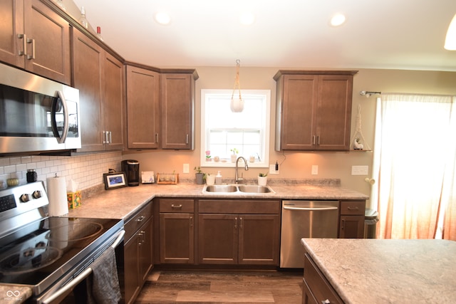 kitchen with pendant lighting, appliances with stainless steel finishes, dark wood-type flooring, and sink