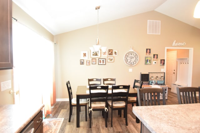 dining space with wood-type flooring, vaulted ceiling, and a chandelier