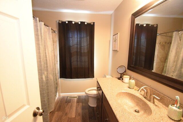 bathroom featuring walk in shower, wood-type flooring, vanity, and toilet