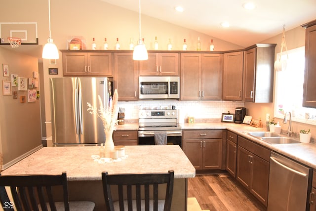 kitchen featuring pendant lighting, lofted ceiling, appliances with stainless steel finishes, and sink