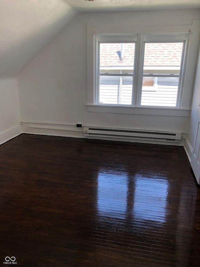 additional living space with dark hardwood / wood-style floors, vaulted ceiling, and a baseboard heating unit