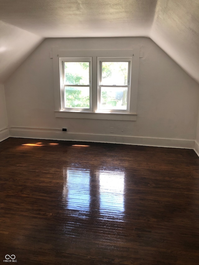 additional living space featuring lofted ceiling and dark hardwood / wood-style floors