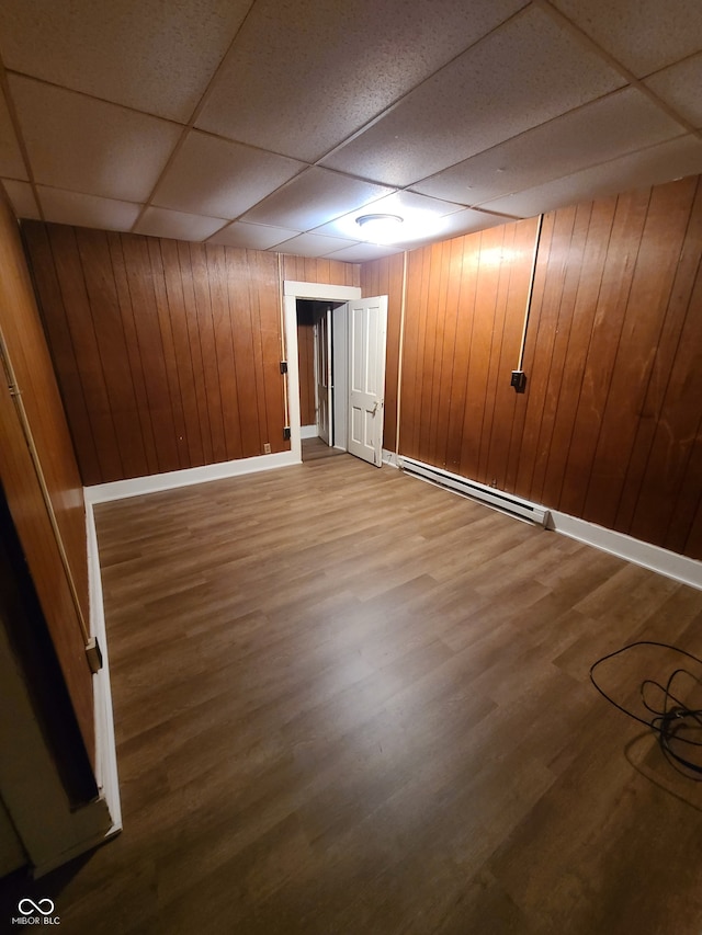 basement featuring wood walls, hardwood / wood-style floors, and a baseboard radiator