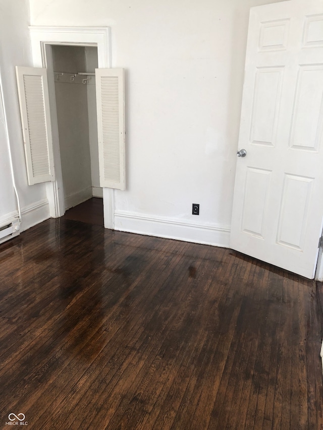 unfurnished bedroom with dark wood-type flooring and a closet