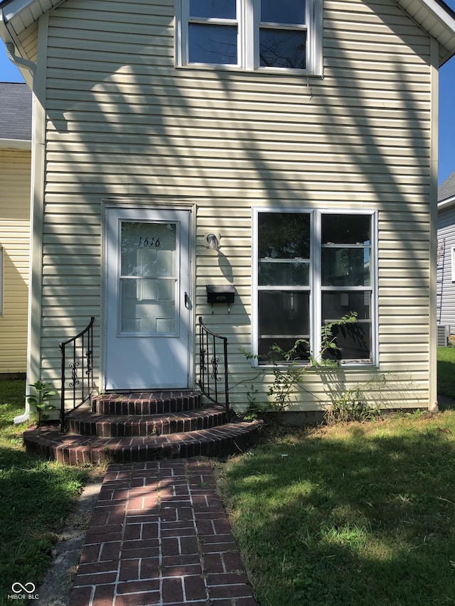 view of exterior entry featuring a lawn