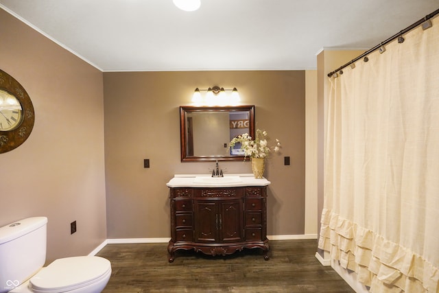 bathroom featuring toilet, vanity, ornamental molding, and hardwood / wood-style flooring