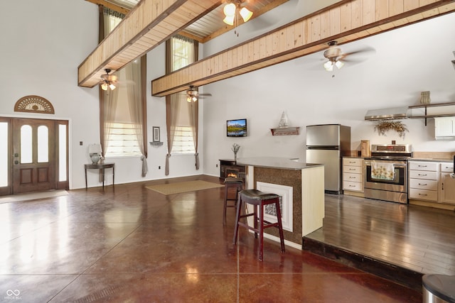 kitchen with a high ceiling, ventilation hood, dark hardwood / wood-style floors, a kitchen bar, and stainless steel appliances