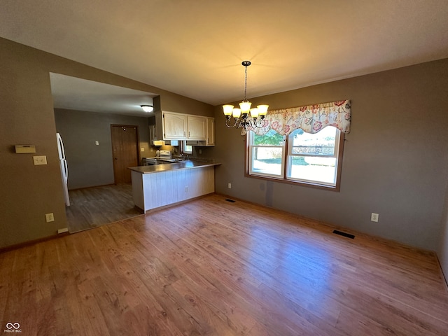 interior space with a notable chandelier, light hardwood / wood-style flooring, and vaulted ceiling