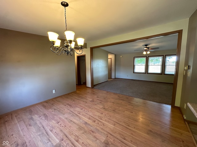 unfurnished room featuring ceiling fan with notable chandelier and wood-type flooring