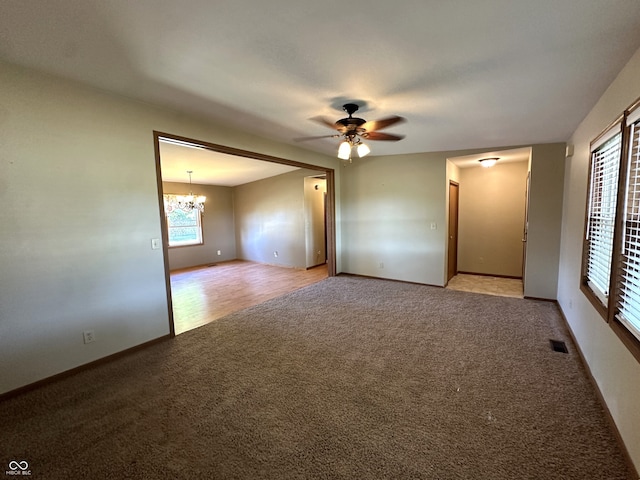 empty room with ceiling fan with notable chandelier and light hardwood / wood-style flooring