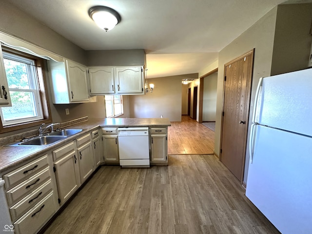 kitchen with white cabinets, white appliances, kitchen peninsula, hardwood / wood-style flooring, and sink