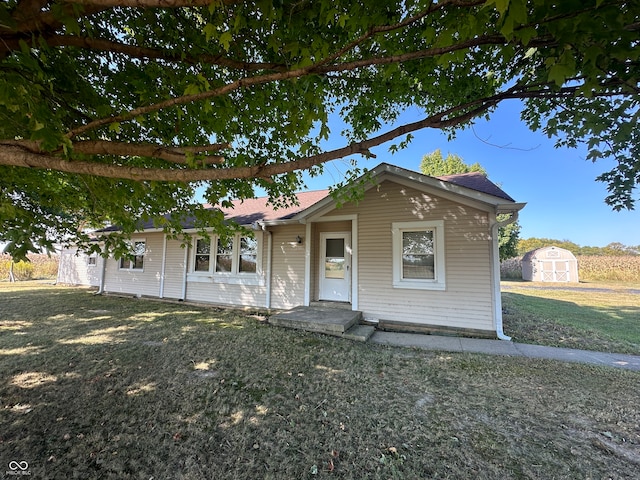 view of front of property featuring a front yard and a shed