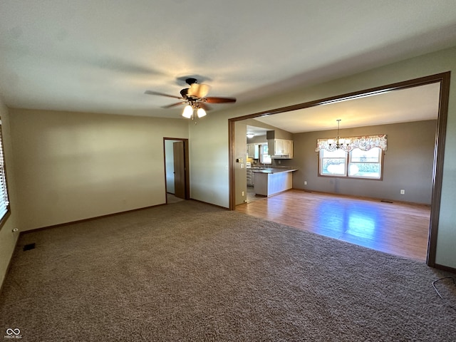 unfurnished living room with ceiling fan with notable chandelier and light hardwood / wood-style floors