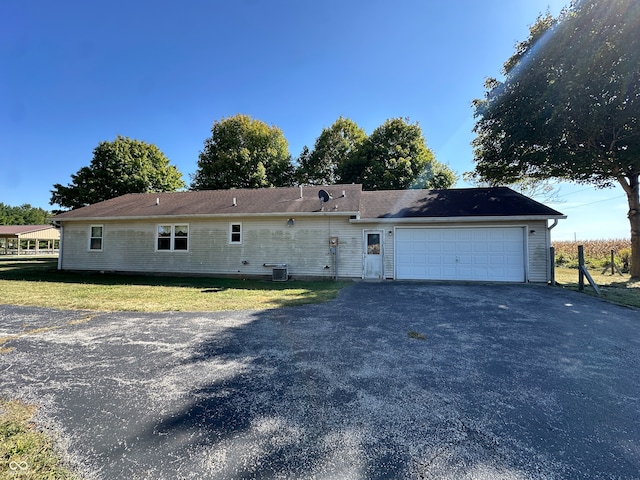 exterior space featuring a garage, a front lawn, and central AC